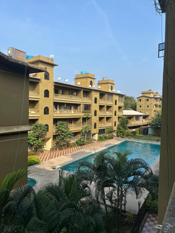 Blick auf ein Gebäude mit einem Pool und Palmen in der Unterkunft Formosa siolim in Velha Goa