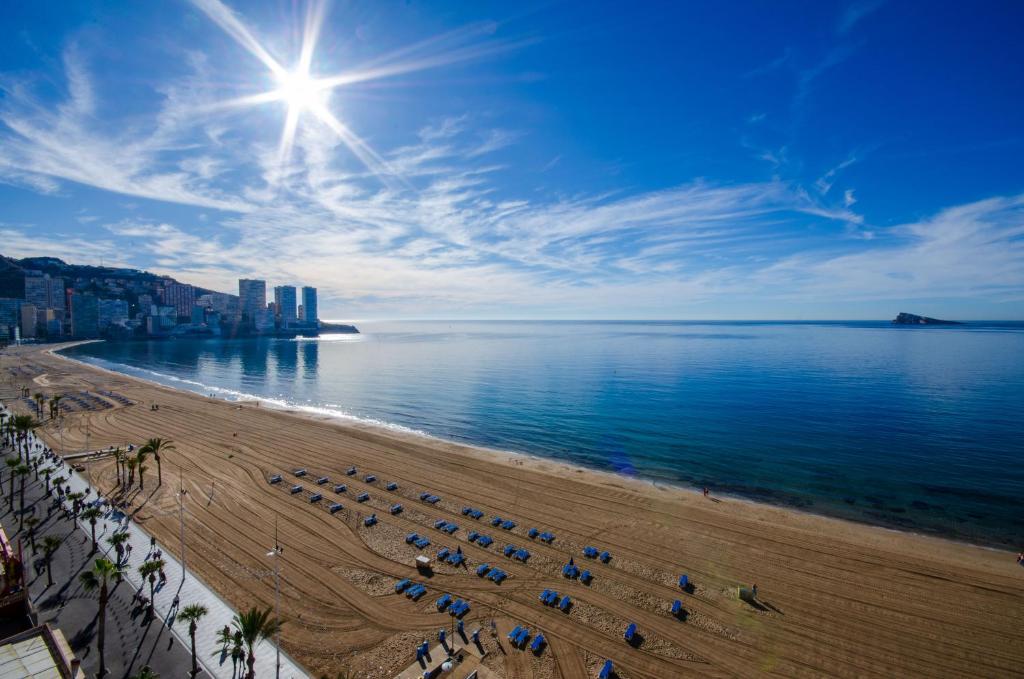 a beach with chairs and umbrellas and the ocean at GEMELOS 10 Levante Beach in Benidorm