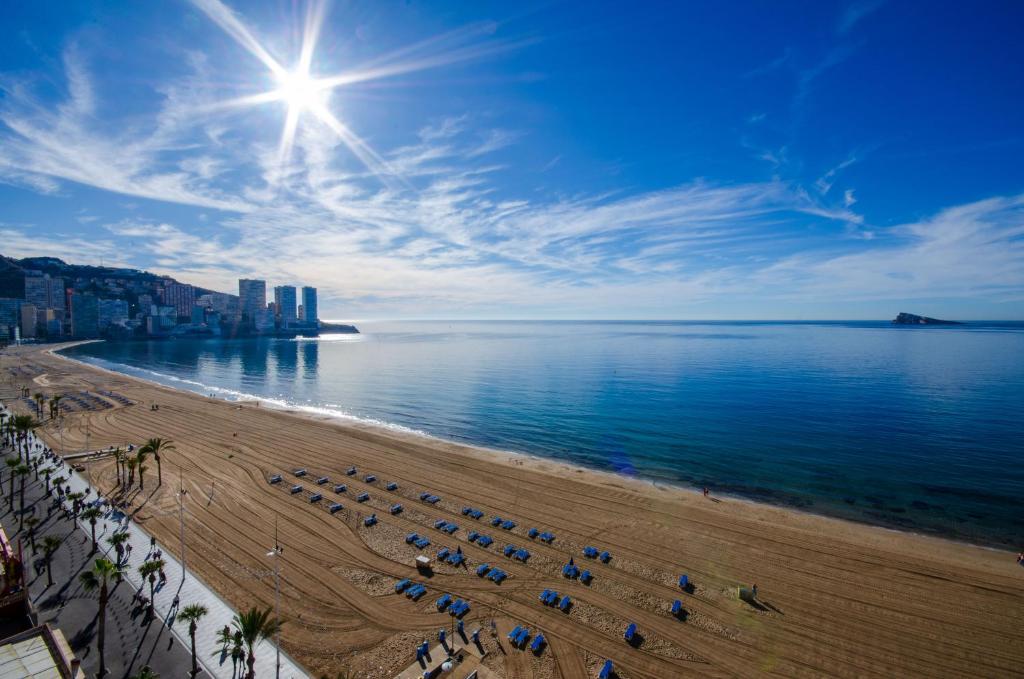 una playa con sillas y sombrillas y el océano en GEMELOS 10 Levante Beach, en Benidorm