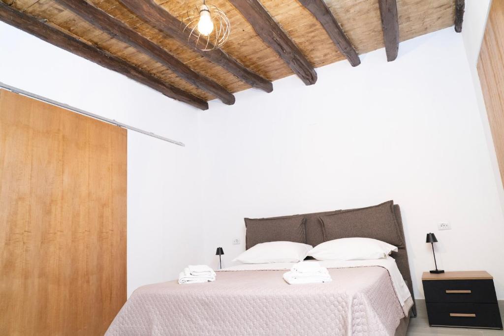a white bedroom with a bed and a wooden ceiling at Politeama house in Palermo