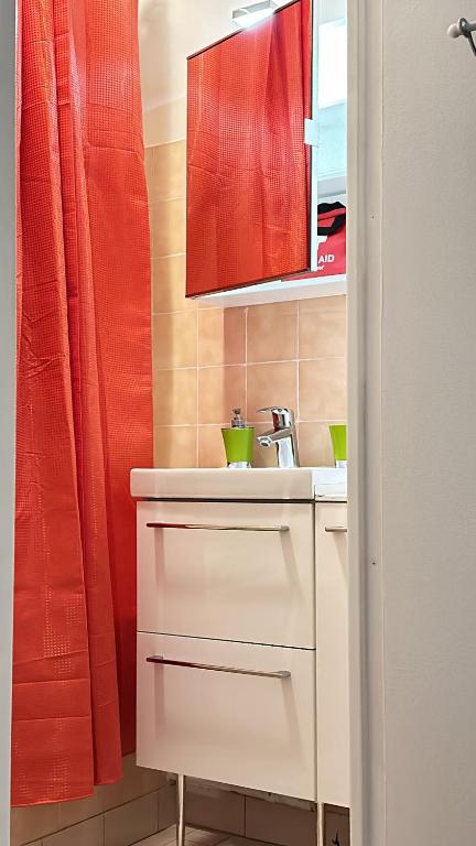 a bathroom with a sink and a red shower curtain at Très beau studio proche de Disneyland et de Paris in Ozoir-la-Ferrière