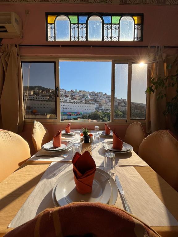 uma sala de jantar com uma mesa e vista para a cidade em Diyar Timnay em Moulay Idriss