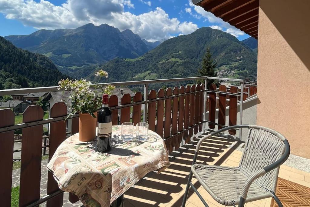 uma mesa com copos de vinho numa varanda com montanhas em Sém chì, relaxing cottage in the mountains em Gromo
