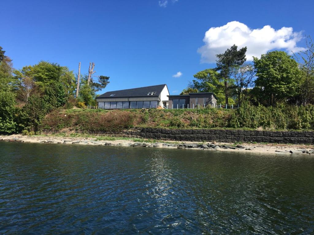 a house on the shore of a body of water at Ferrypoint House in Rhu
