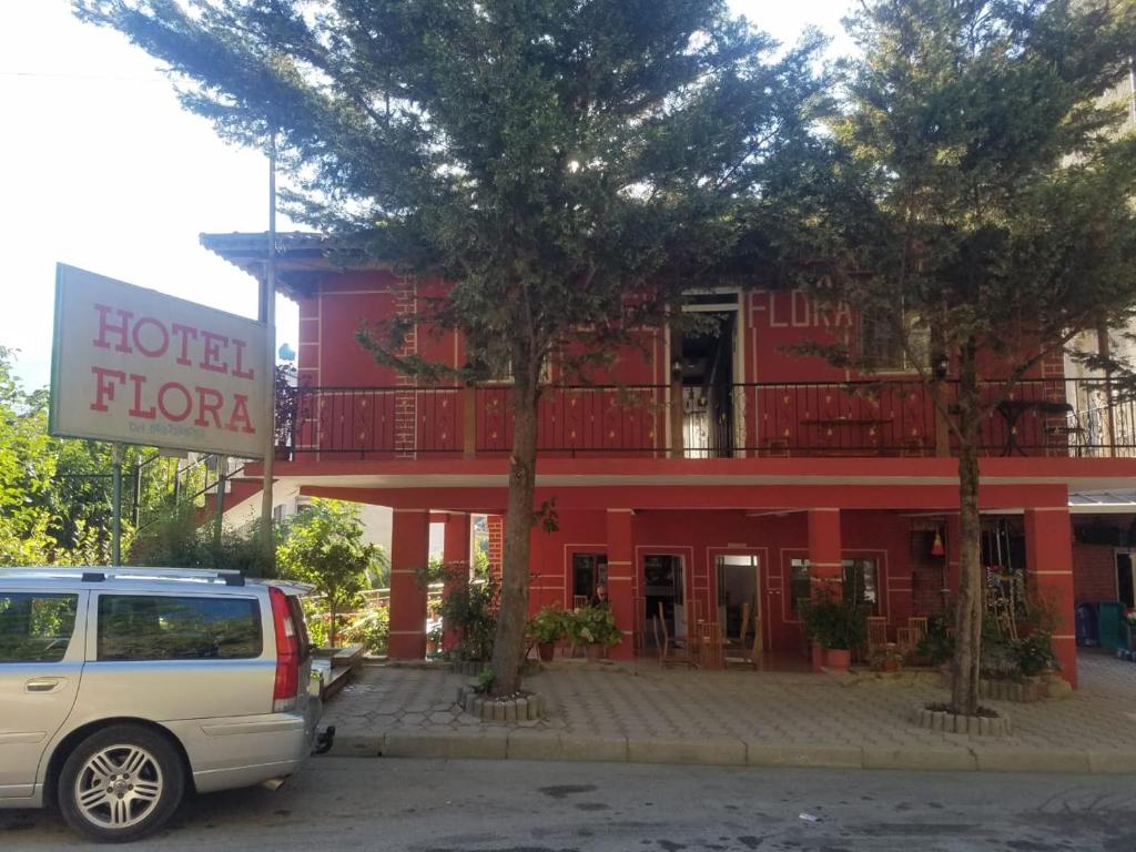 a white van parked in front of a red hotel at Hotel Flora in Çorovodë