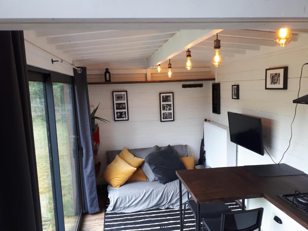 een woonkamer met een bank en een tafel bij Tiny house, sauna hot tub Gesves Namur Ardennes in Gesves