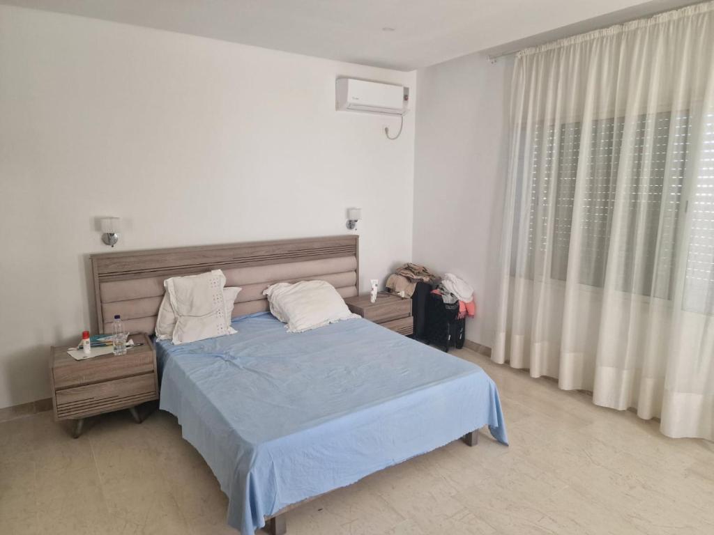 a bedroom with a blue bed and a window at Villa Smiley in Hammamet