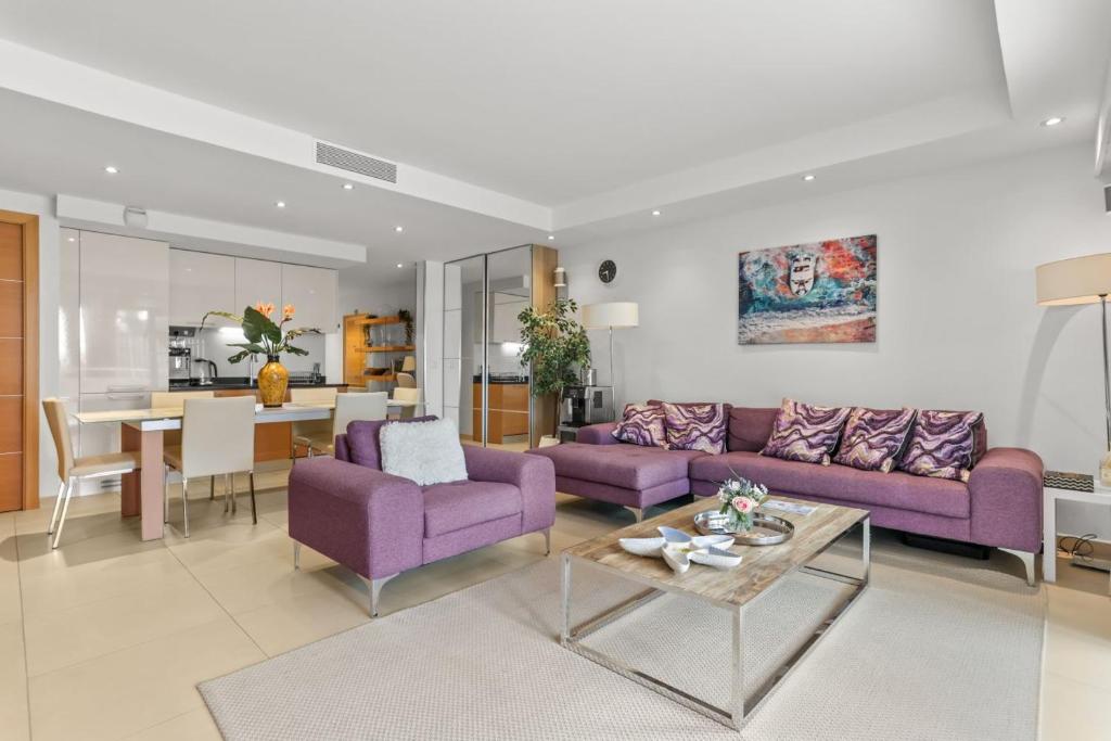 a living room with purple couches and a table at Chic & Modern 2 Bed Apartment in Théoule-sur-Mer with Pool Access & Beach Proximity in Théoule-sur-Mer