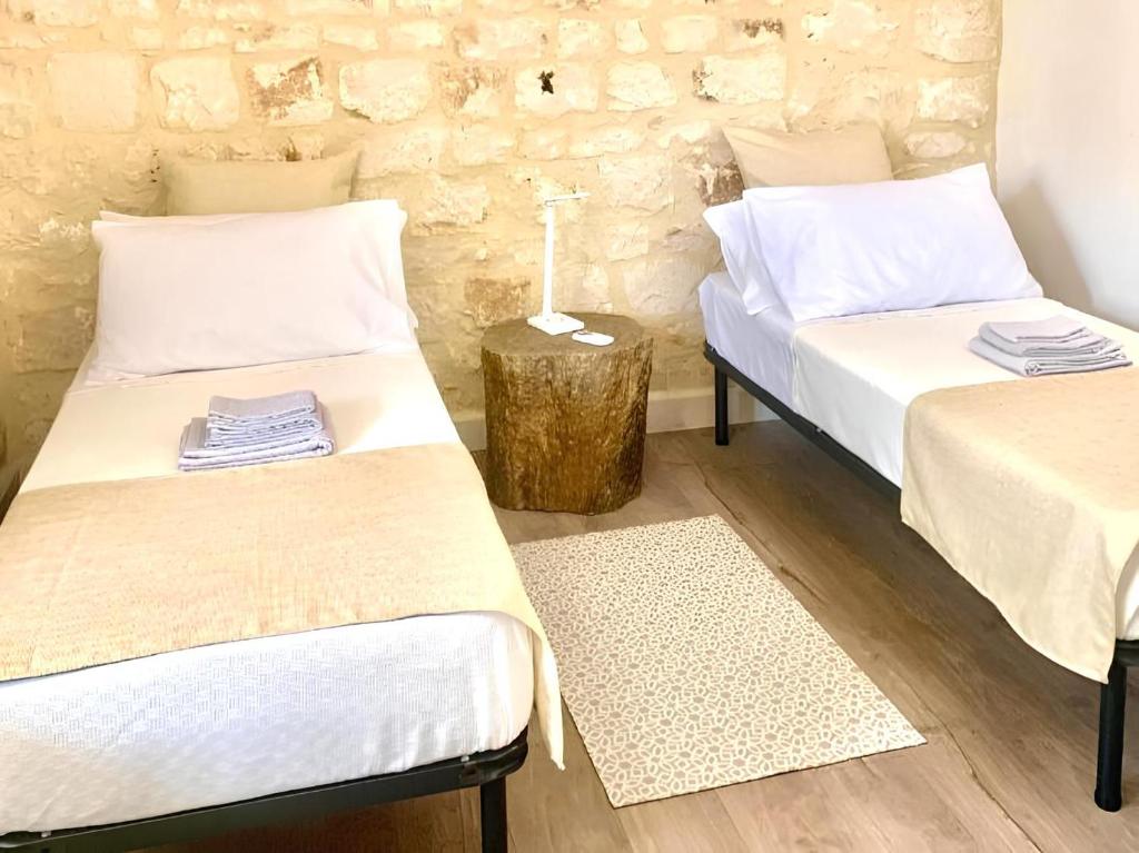 2 łóżka pojedyncze w pokoju z kamienną ścianą w obiekcie Casa DaviRì w mieście Modica
