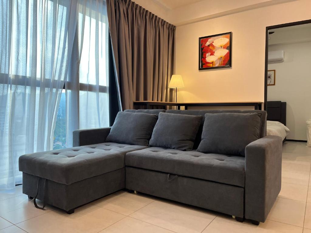 uma sala de estar com um sofá em frente a uma janela em Family friendly 3 bedroom 8-10pax @Urban Suites em George Town