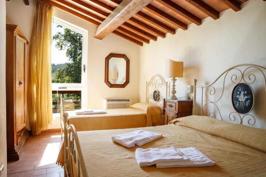 1 dormitorio con 2 camas y ventana en Agriturismo Podere Bucine Basso, en Lari