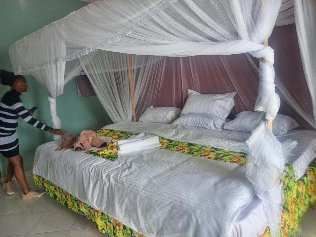a woman is standing next to a large bed at African Tent Resort in Kabale
