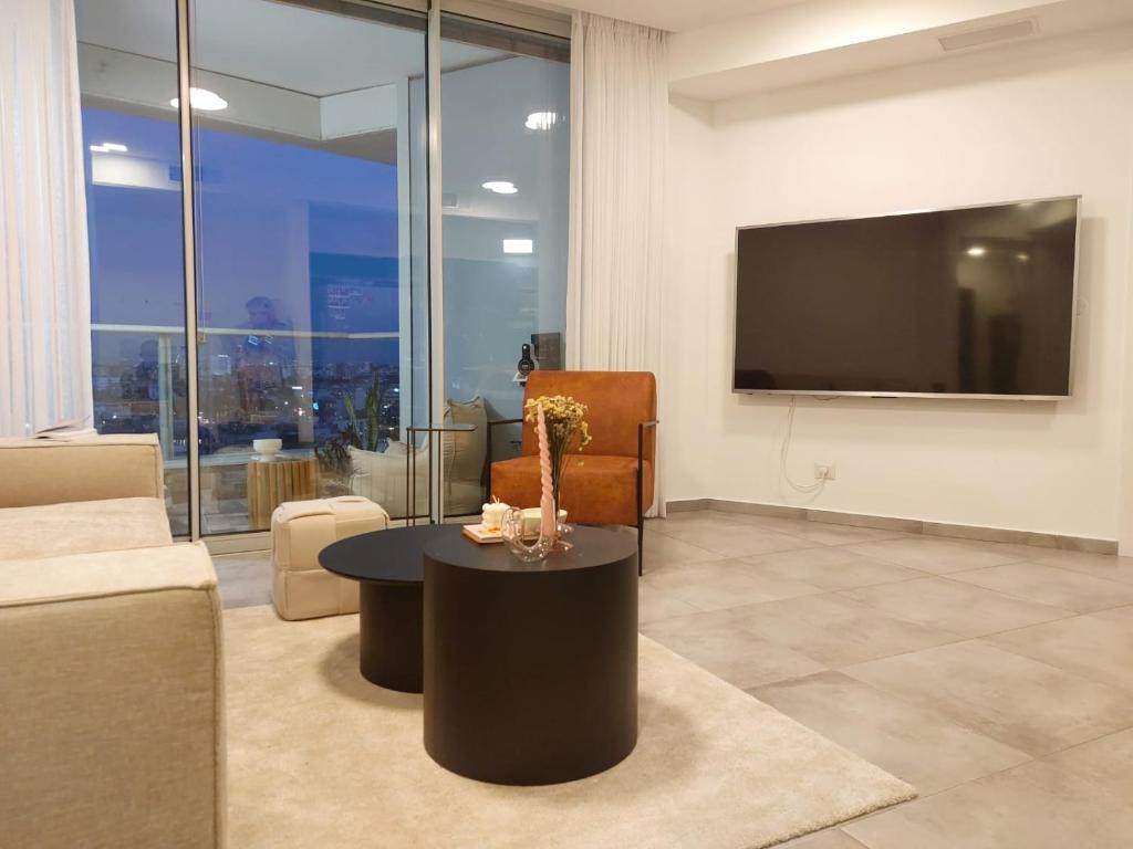 a living room with a couch and a table and a tv at Gindi Tower Apartments TLV in Tel Aviv