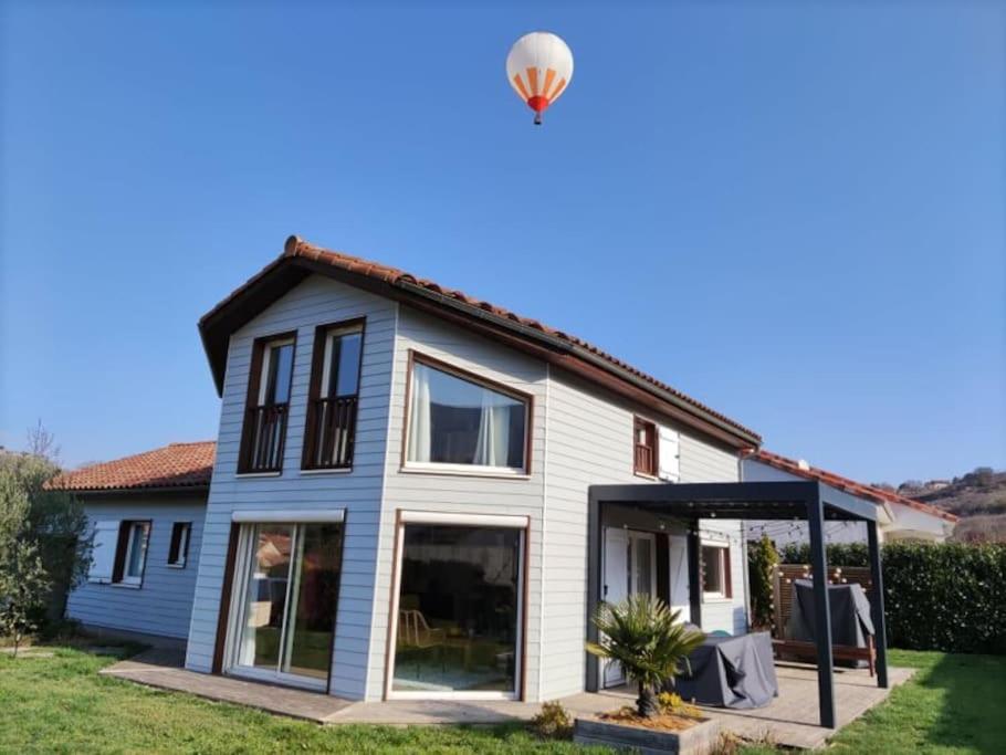 uma casa com um balão de ar quente no céu em Maison avec jardin au pied du Viaduc de Millau em Creissels