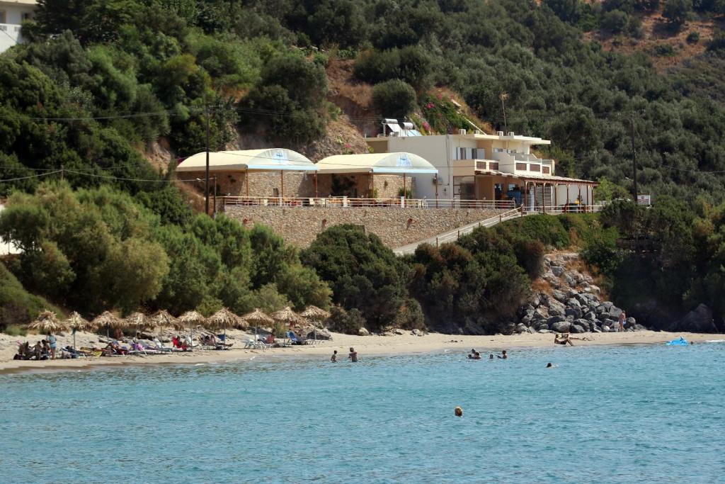 a house on a hill next to a beach at Santa Marina Apartments in Rodakino