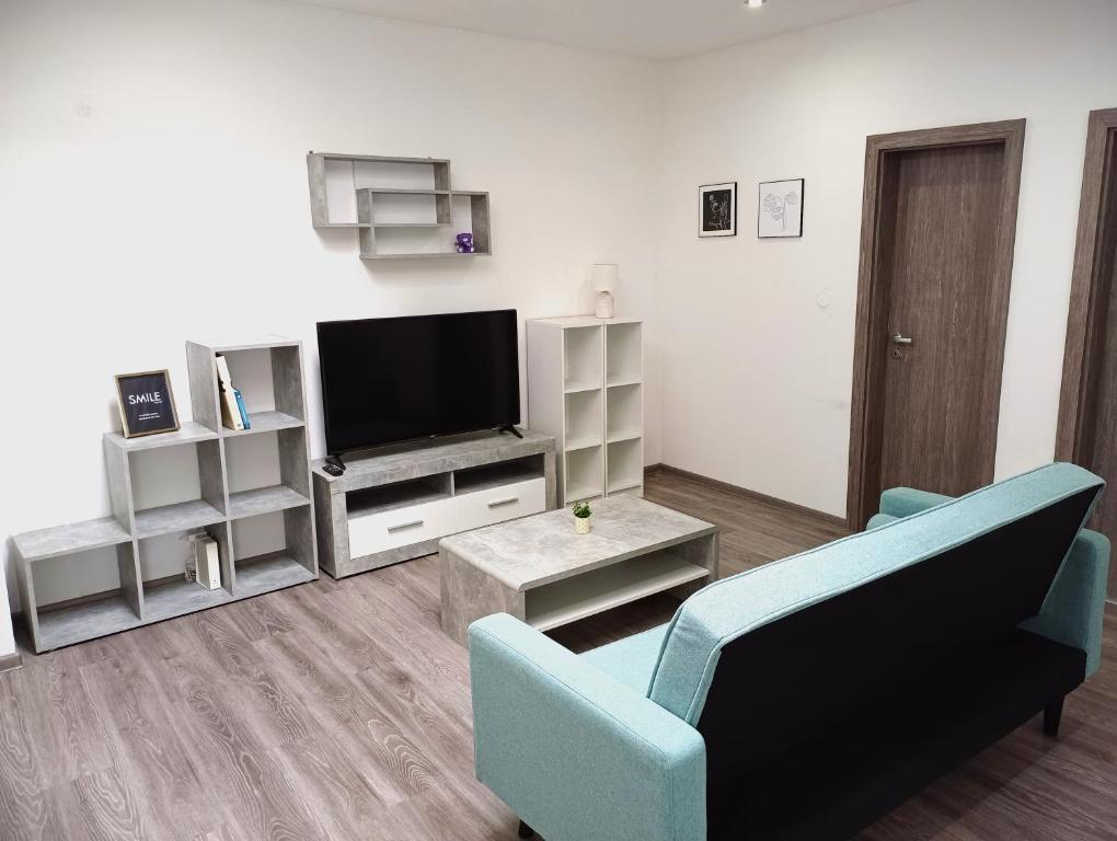 sala de estar con TV y sofá azul en Apartmán Marty, en Nové Zámky