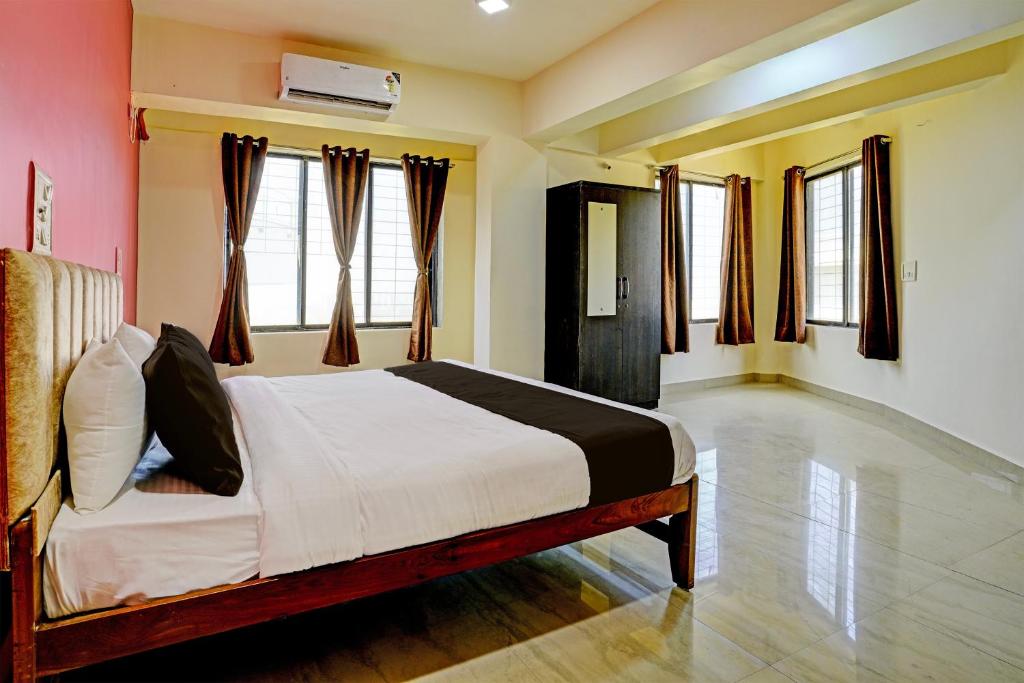 um quarto com uma cama num quarto com janelas em Collection O Sunset Residency em Mumbai