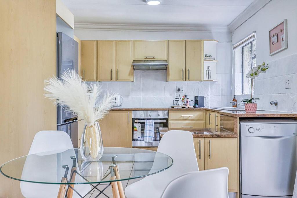 eine Küche mit einem Glastisch und weißen Stühlen in der Unterkunft The Cottage-1 Bed-pool-bbq-fibre-solar-samrand in Centurion