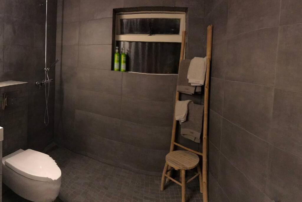 a bathroom with a toilet and a shower and a stool at COZY APPARTMENT Free parking in Reykjavík