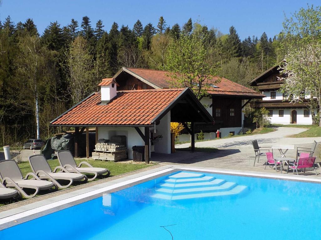 a swimming pool with lounge chairs and a house at Ferienwohnung Hauzenberg Blick FeWo306 in Hauzenberg