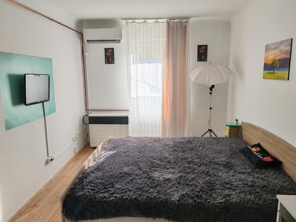 a bedroom with a bed and a lamp and a window at Skylark Relax Apartman in Szeged