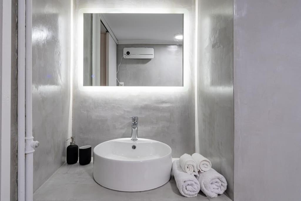 La salle de bains est pourvue d'un lavabo, d'un miroir et de serviettes. dans l'établissement Central Elegant Flat, à Patras