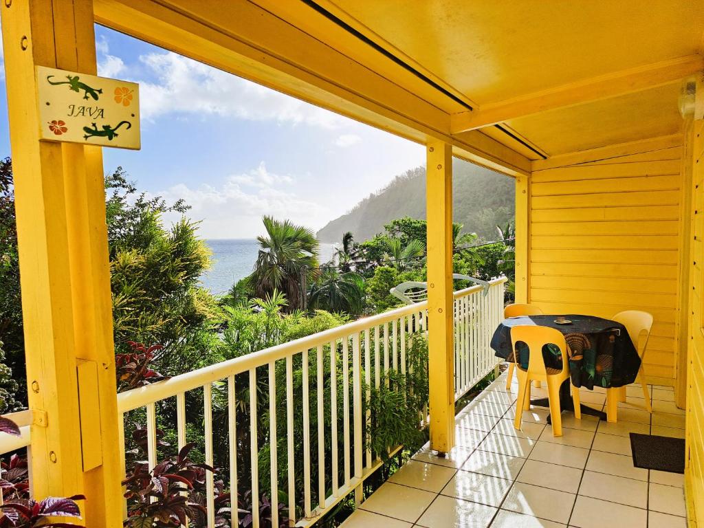 a yellow house with a balcony with a view of the ocean at Bungalow Java - Bassin Manapany-Les-Bains in Saint-Joseph