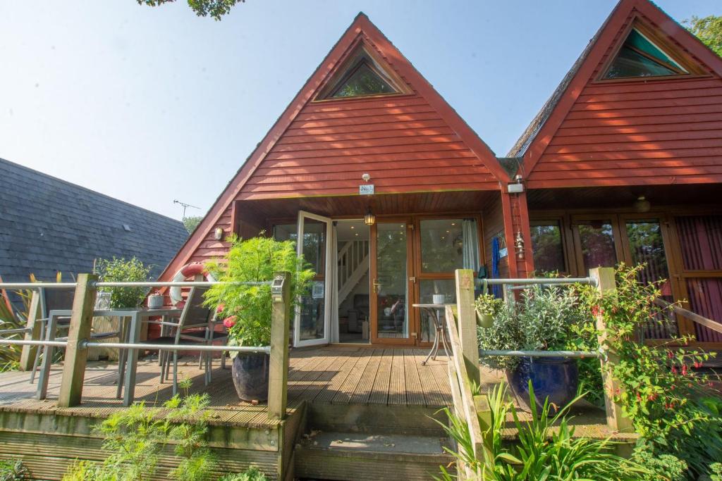 een huis met een houten veranda met planten erop bij Chalet One in Deal
