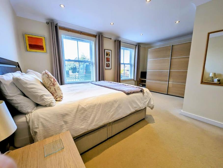 a bedroom with a bed in a room with windows at SoHot Stays-Garden Apt-Free Parking Ground Flr in Kent