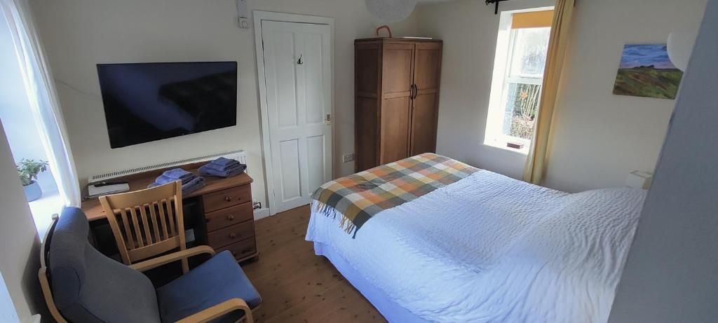 a bedroom with a bed and a chair and a television at Private annex to Victorian villa, with kitchen and Free parking in Todmorden