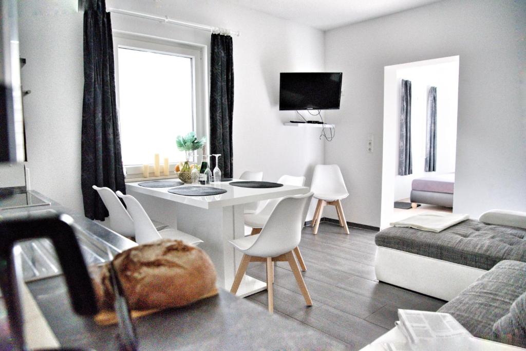 - un salon avec une table et des chaises blanches dans l'établissement Haff-Ostseeferienhaus Nebengebäude, à Mönkebude