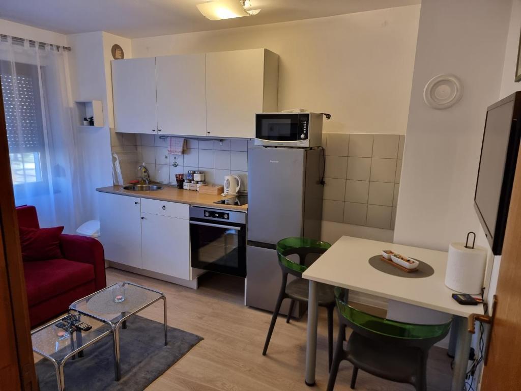 una cocina con armarios blancos y una mesa pequeña con mesa en Studio apartman Šapudl en Vukovar
