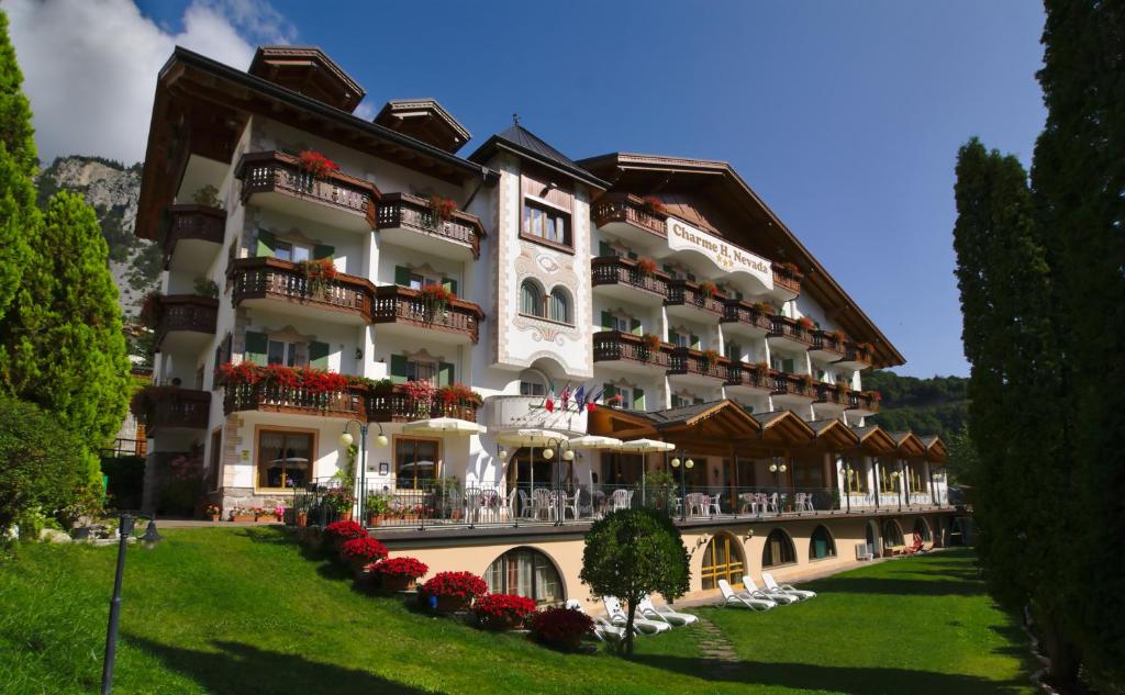 a large building with a large balcony overlooking the ocean at Charme Hotel Nevada in Molveno