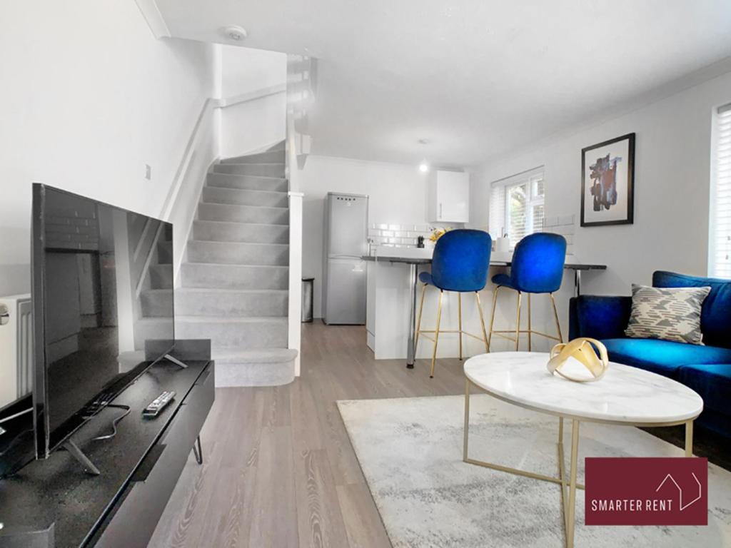uma sala de estar com cadeiras azuis e uma escada em Lightwater - 1 Bedroom Terraced House em Bagshot