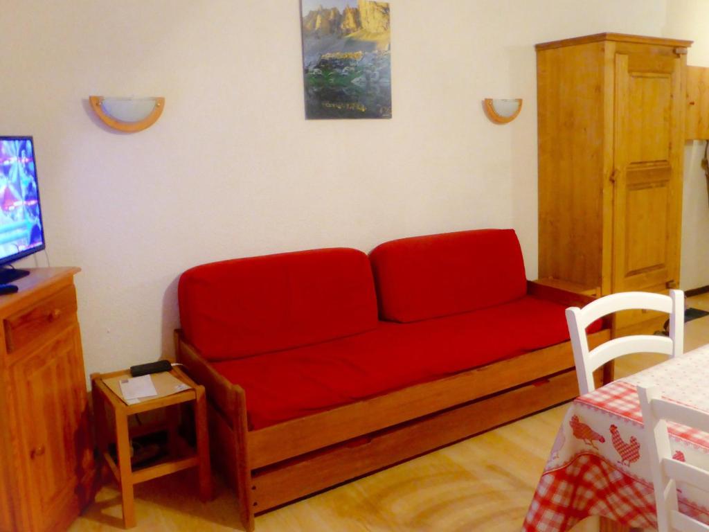 - un canapé rouge dans le salon doté d'une télévision dans l'établissement Studio confortable pour 4 pers, balcon, proche télésiège, parking privé, animaux acceptés - FR-1-263-379, à Valloire