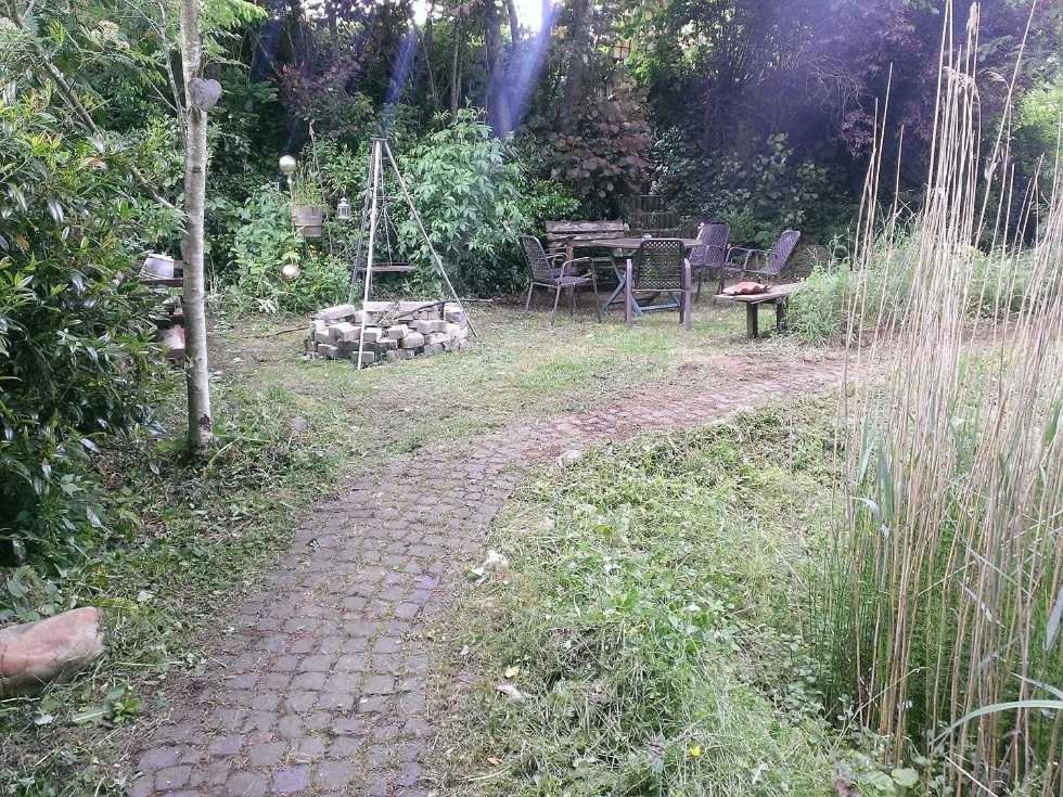 um caminho de tijolos num jardim com uma mesa e cadeiras em Ferienwohnungen Willrich em Blankenheim