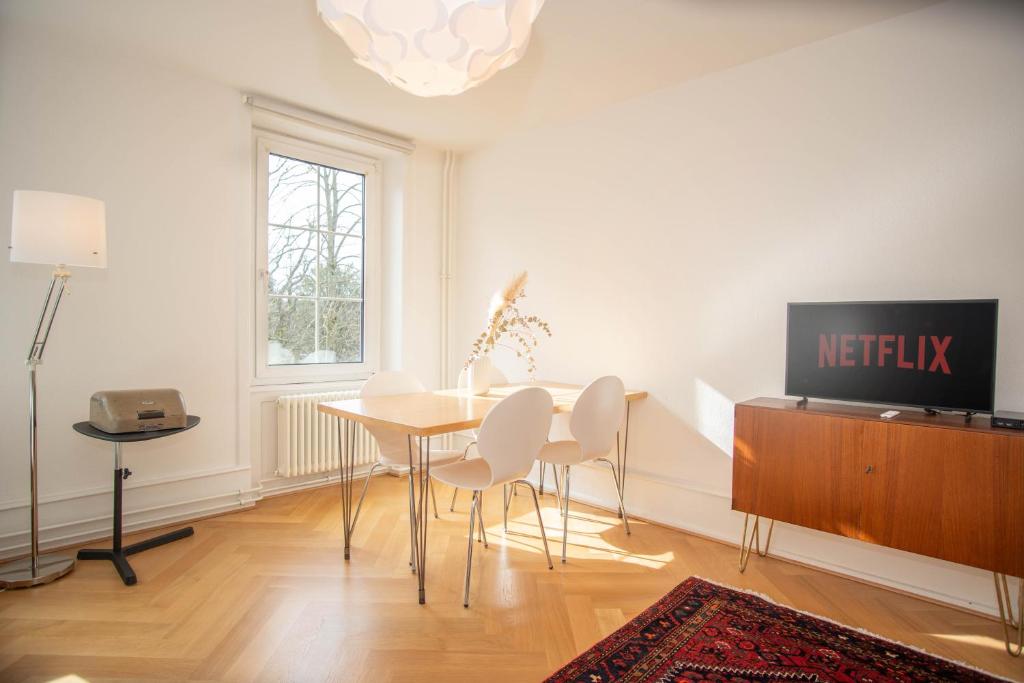 ein Esszimmer mit einem Tisch und einem TV in der Unterkunft Spacious apartment next to park with free BaselCard in Basel