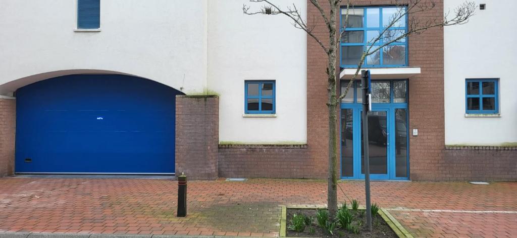 un edificio con una puerta de garaje azul junto a un árbol en Appartement Wellington D3 Knokke full service et parking en Knokke-Heist
