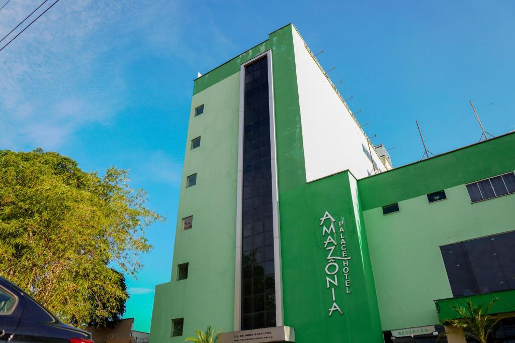 a green and white building with a blue sky in the background at Amazônia Palacce Hotel in Marabá