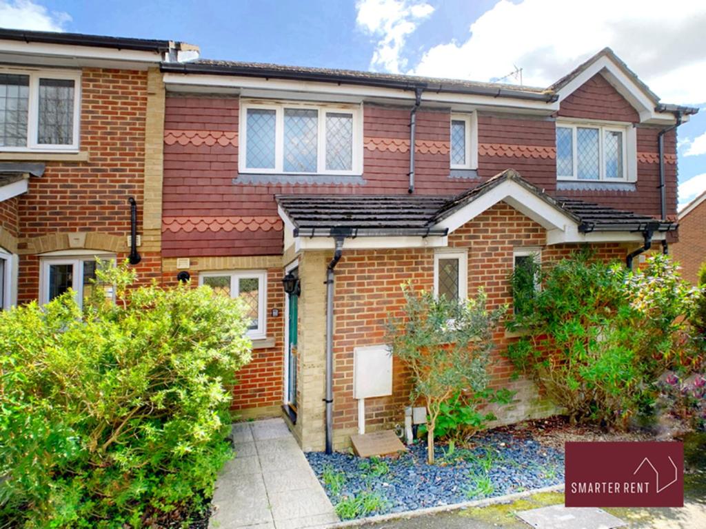 Brookwood的住宿－Knaphill, Woking - 2 Bedroom House - Garden and Parking，前面有灌木丛的红砖房子