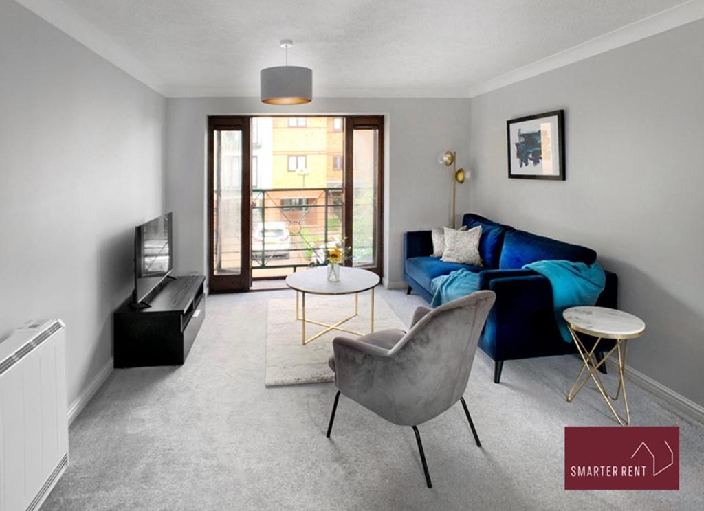 sala de estar con sofá azul y mesa en Maidenhead - Gated 2 Bedroom Flat, Close To Train Station en Maidenhead