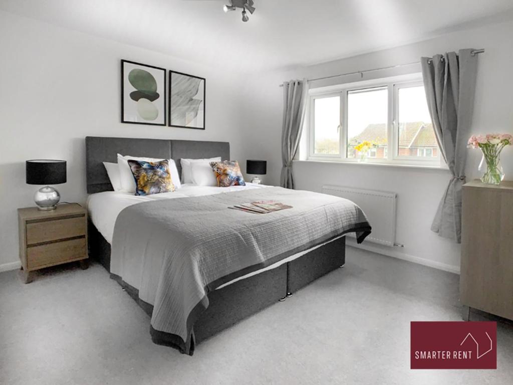 Farnborough - Modern 2 Bedroom House في Blackwater: غرفة نوم بسرير كبير ونافذة