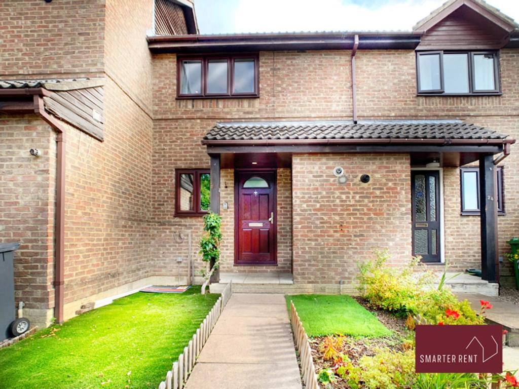 una casa de ladrillo con una puerta roja y un patio en West End, Woking - 2 Bed House With Parking and Garden, en Bisley