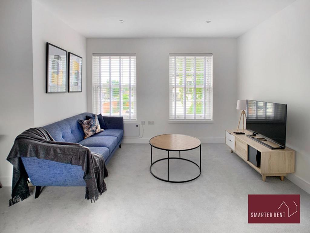 a living room with a blue couch and a table at Eton, Windsor - 1 Bedroom First Floor Apartment - Parking in Eton