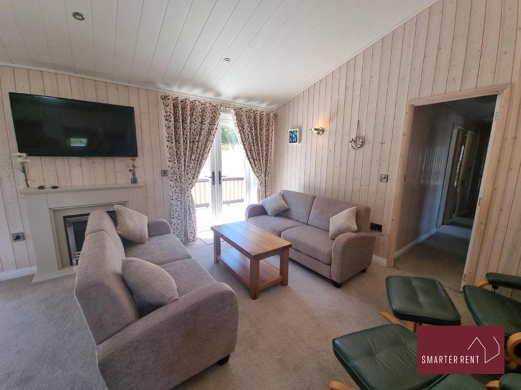 a living room with two couches and a tv at Milford on Sea - 4 Bedroom Lodge in Shorefield Country Park in Milford on Sea