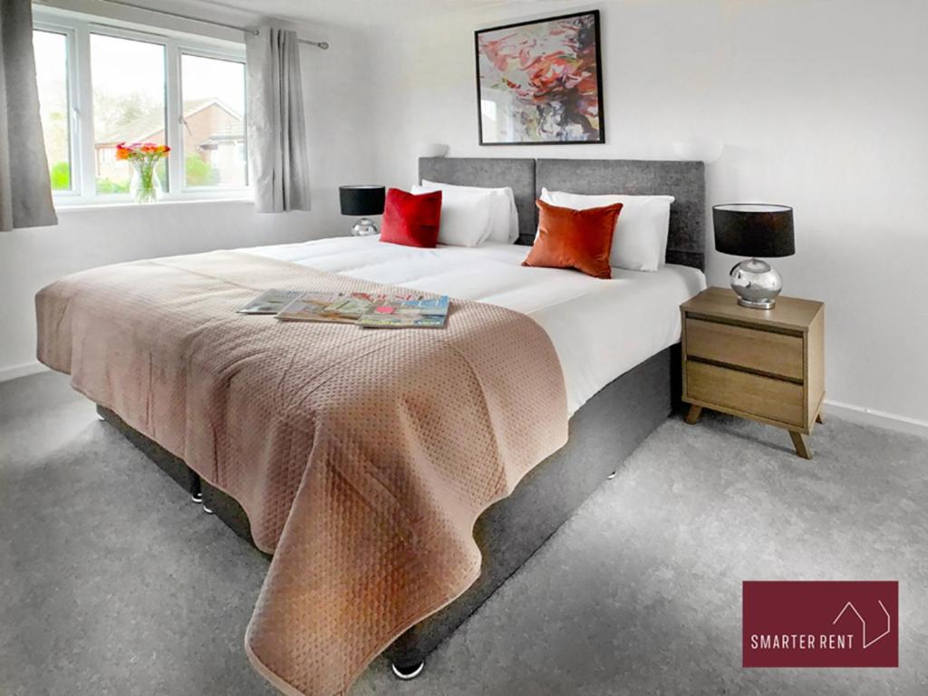 a bedroom with a large bed with red pillows at 2 Bed House with Garden, Woking in Chobham