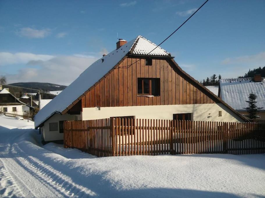 ein Holzhaus mit einem Zaun im Schnee in der Unterkunft Chalupa na Vysočině in Sněžné