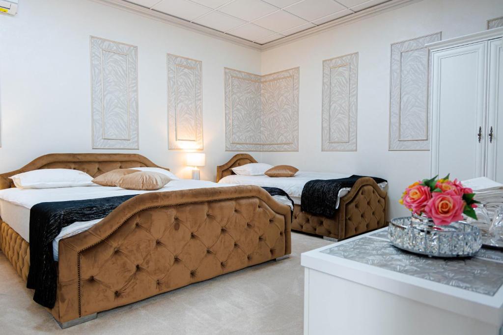 トゥルグ・ジウにあるPensiunea Infinityのベッドルーム1室(ベッド2台、花のテーブル付)