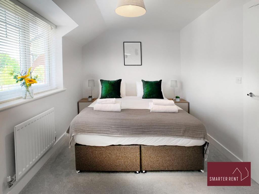 a bedroom with a large bed with green pillows at Wokingham - 2 bed House with garden in Wokingham