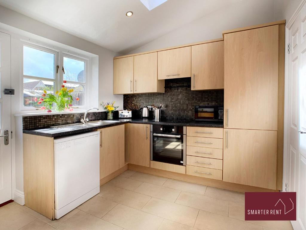 a kitchen with wooden cabinets and a window at Ascot - Immaculate 2 bed House with parking in Ascot